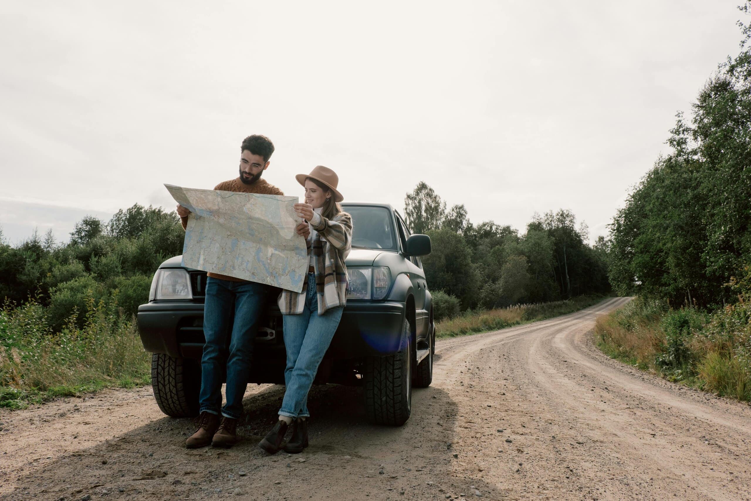 Couple looking at map in front of vehicle